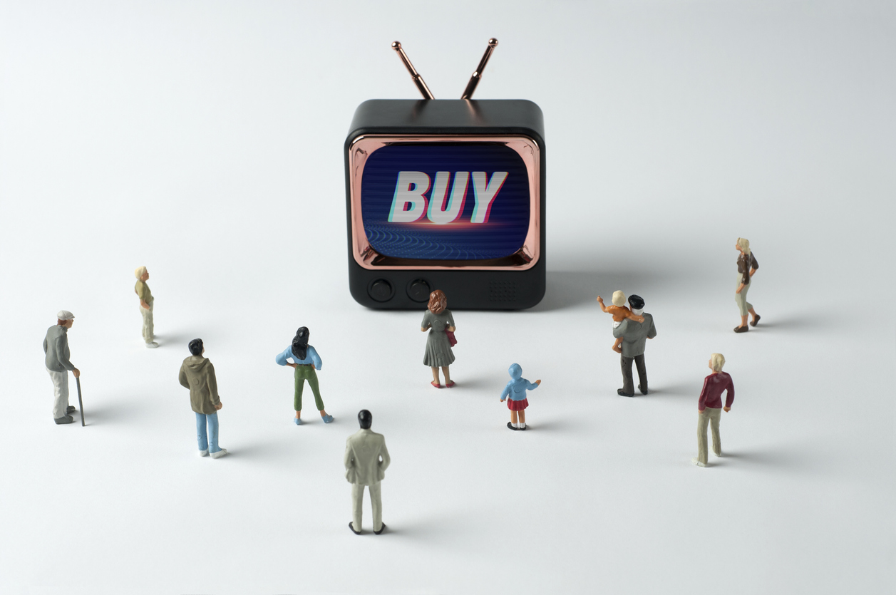 People figurines watching "Buy" instruction on TV.