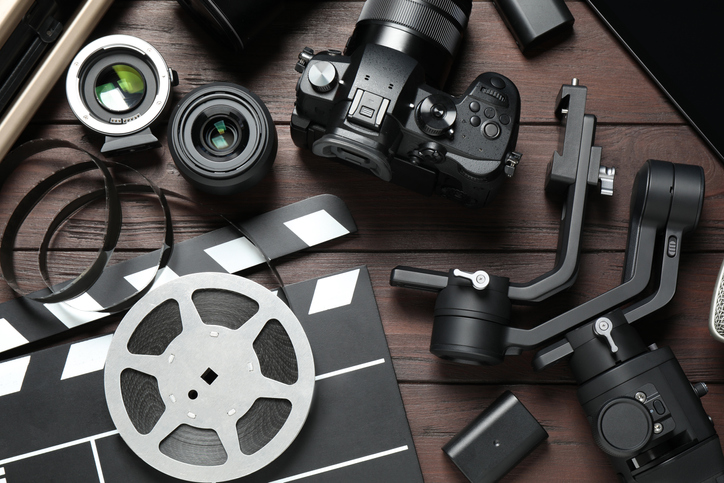 Flat lay composition with camera and video production equipment on brown wooden background