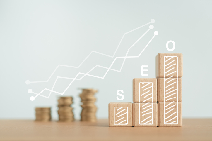 SEO, Search Engine Optimization ranking concept. Wooden cubes block with increasing graph and blurred coins with SEO alphabet